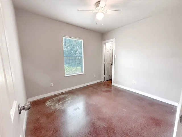 an empty room with a chandelier fan and windows