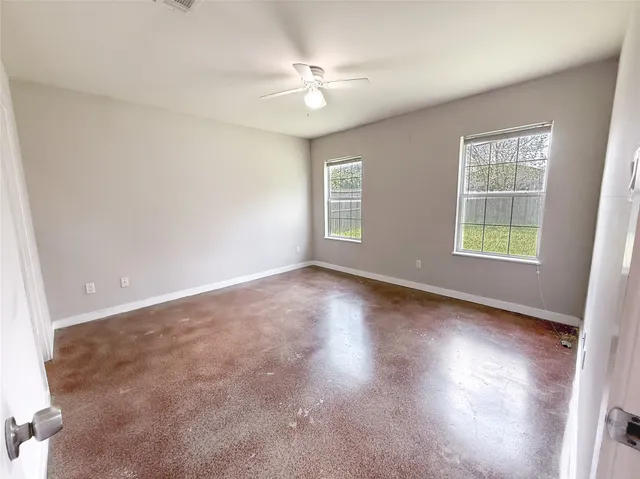 an empty room with windows and ceiling fan