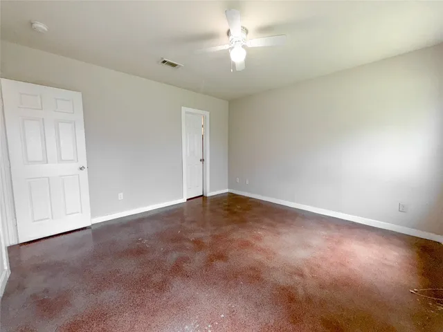 an empty room with a chandelier fan and windows