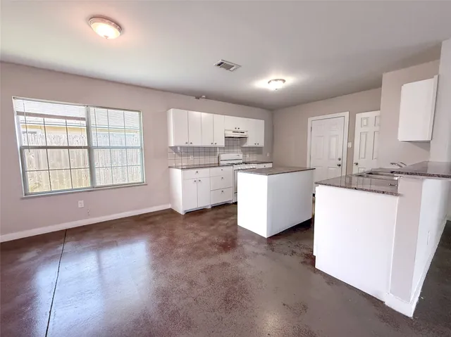 a kitchen with kitchen island a sink a stove a refrigerator cabinets and a window