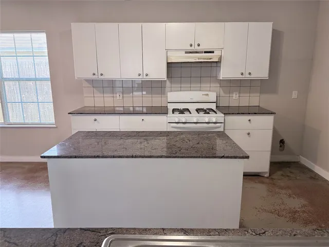 a kitchen with granite countertop a sink stove and cabinets