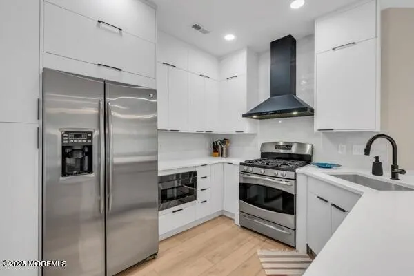 a kitchen with a sink dishwasher a stove and a dining table with wooden floor
