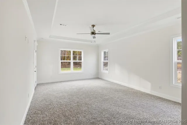 an empty room with chandelier fan and windows
