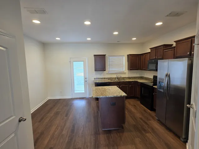 a kitchen with kitchen island wooden floors appliances and cabinets