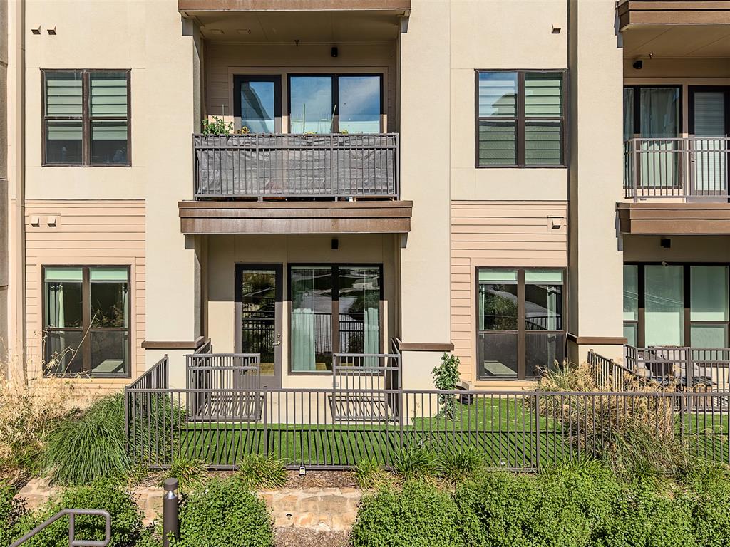 2700 Old Denton Road, Unit 1044 Carrollton, TX 75007 - Photo 20 of 33 Ground-floor patio with artificial turf, surrounded by a black metal fence and stone retaining wall