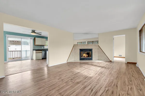 a view of an empty room with window and wooden floor