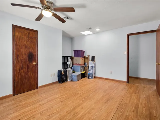a view of a room with wooden floor ceiling fan and windows