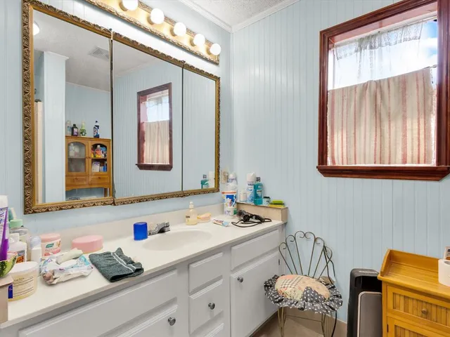 a bathroom with a granite countertop sink mirror vanity and next to a window