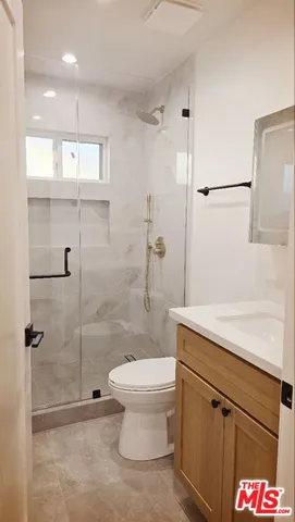a bathroom with a granite countertop sink a toilet and shower