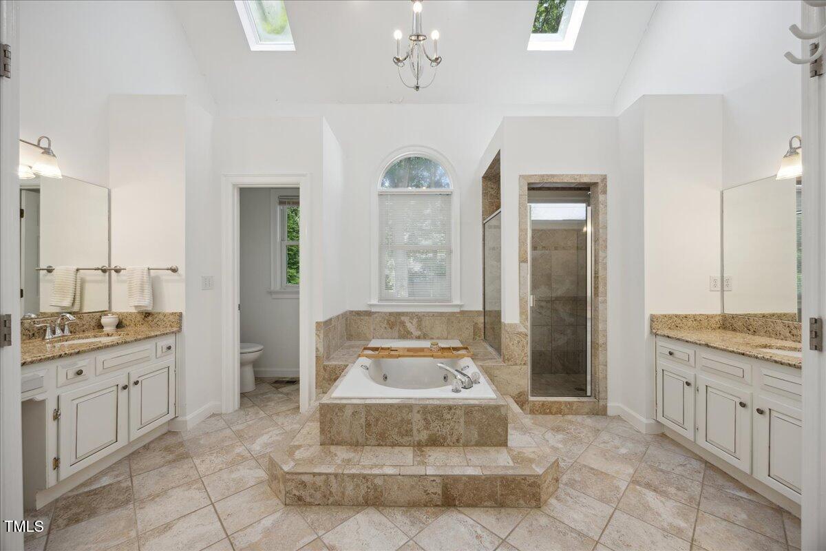 7917 Rooksley Court Raleigh, NC 27615 - Photo 24 of 45 a spacious bathroom with a granite countertop sink a mirror and a shower