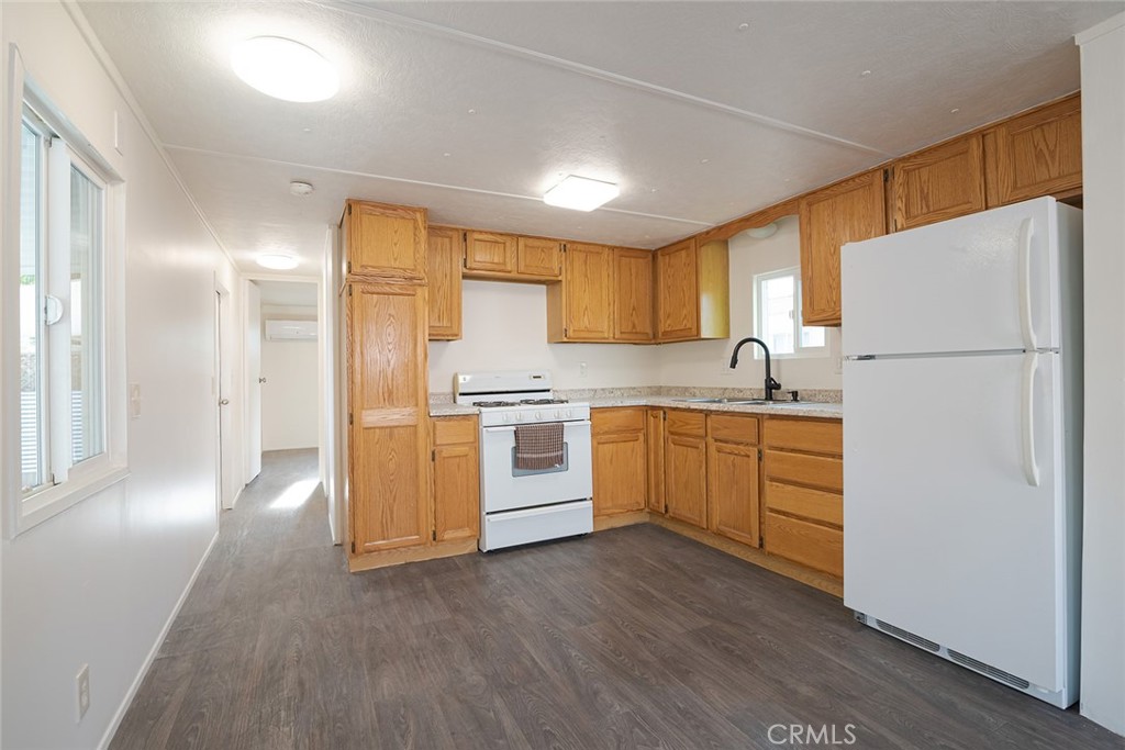 73 Alesandro Road, Unit A Palm Springs, CA 92264 - Photo 7 of 23 a kitchen with a refrigerator a stove top oven a sink and dishwasher with wooden floor