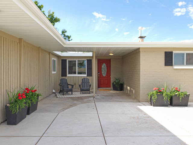 154 East 3000th Street South Bountiful, UT 84010 - Photo 30 of 37 Covered front entry featuring a red paneled door with an oval glass insert, brick exterior, wood-paneled siding, and a concrete driveway