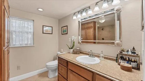a bathroom with a granite countertop sink a toilet and a mirror