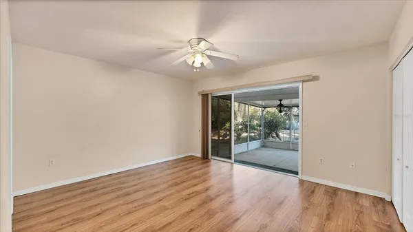 an empty room with wooden floor fan and windows