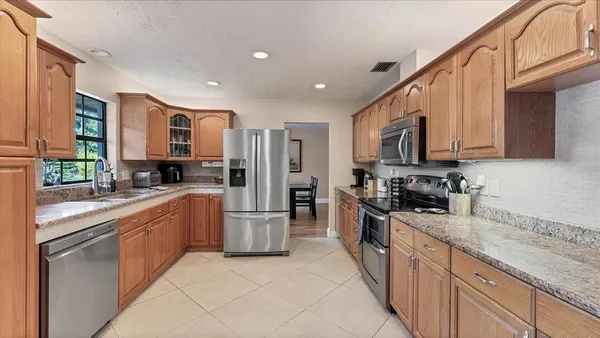 a large kitchen with stainless steel appliances granite countertop a stove top oven a refrigerator a sink and dishwasher