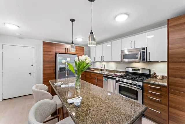 a kitchen with stainless steel appliances granite countertop a stove a sink a refrigerator a stove a dining table and chairs with wooden floor