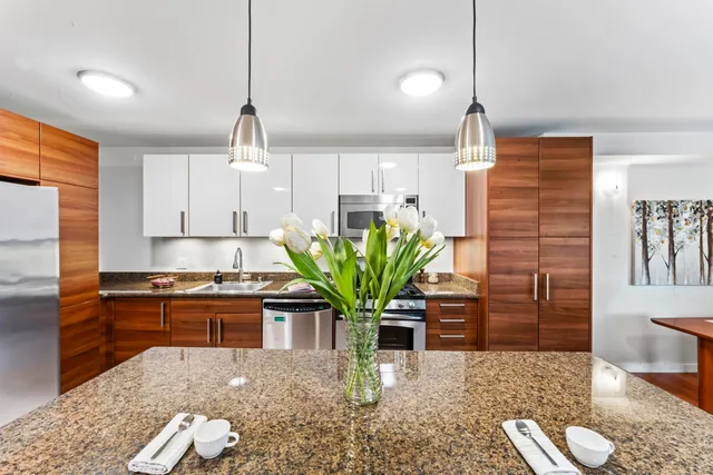 a kitchen with stainless steel appliances kitchen island granite countertop a refrigerator a stove a sink dishwasher and white cabinets with wooden floor