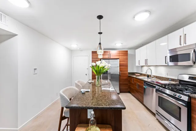 a kitchen with stainless steel appliances granite countertop a stove a sink dishwasher a microwave oven with a dining table and chairs