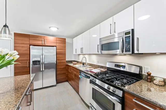 a kitchen with stainless steel appliances granite countertop a stove a sink and a microwave