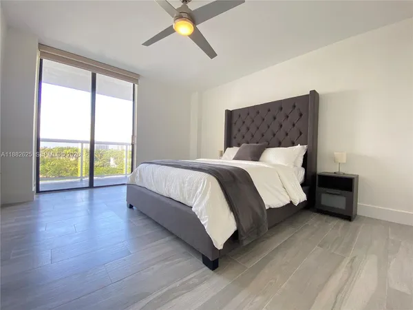 a bedroom with a bed lamp and a large window