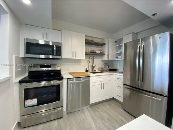 a kitchen with stainless steel appliances a stove a microwave and white cabinets