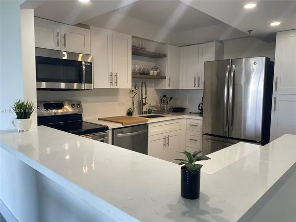a kitchen with stainless steel appliances a sink dishwasher a refrigerator a stove top oven a sink dishwasher and wooden cabinets