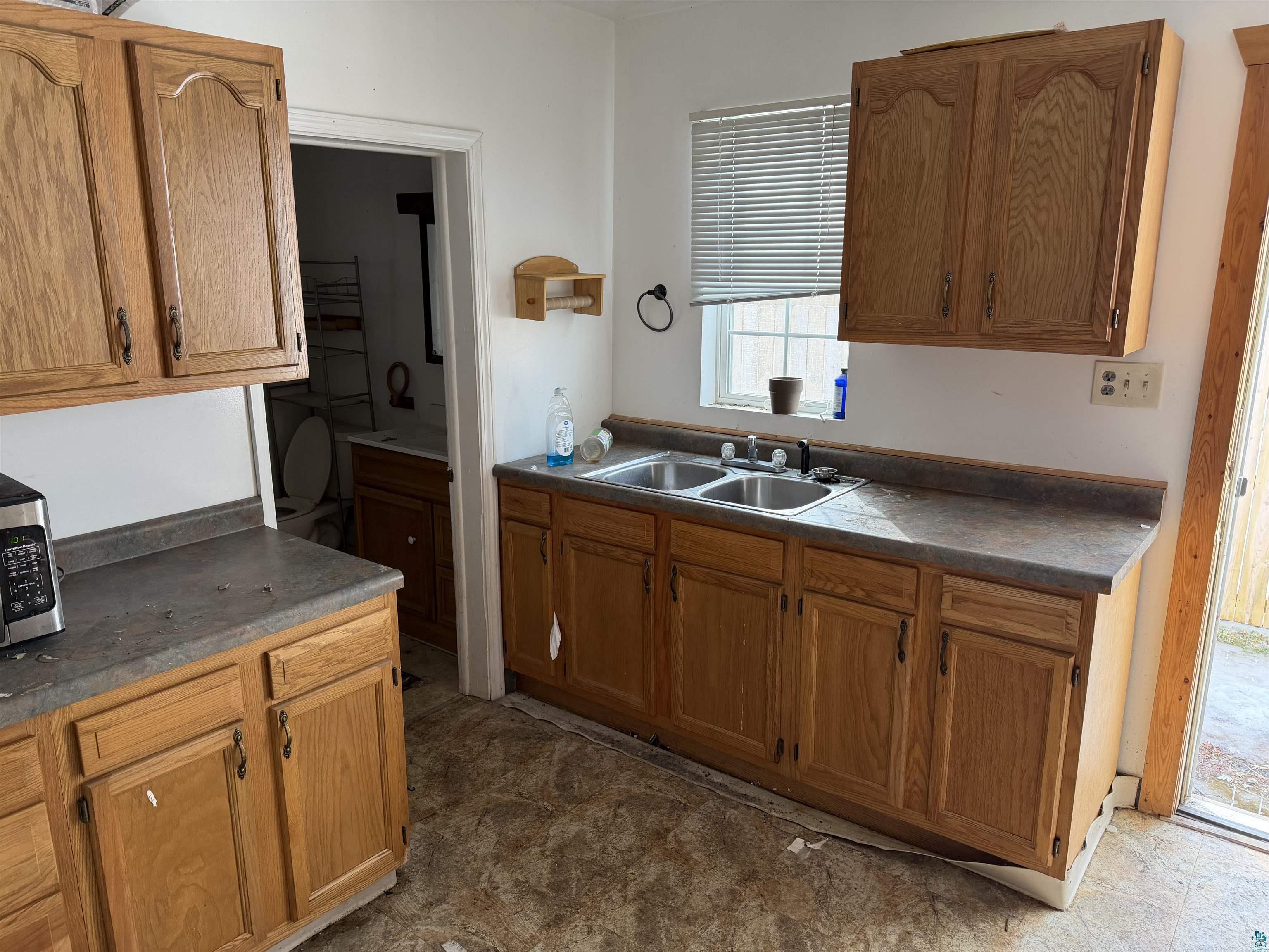 1720 Iowa Avenue Superior, WI 54880 - Photo 6 of 11 Kitchen with stainless steel microwave, dark countertops, wood finish cabinetry, and dark floors