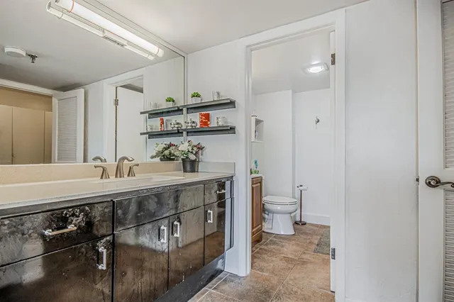 a bathroom with a granite countertop sink a toilet and a shower