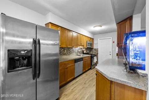 a kitchen with stainless steel appliances granite countertop a refrigerator a oven a sink with island and chairs