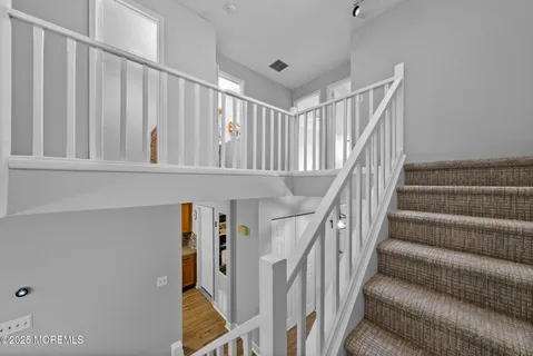 a view of staircase with lots of frames on wall and a window