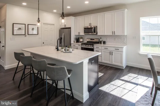 a kitchen with stainless steel appliances a stove a sink a microwave a refrigerator and cabinets