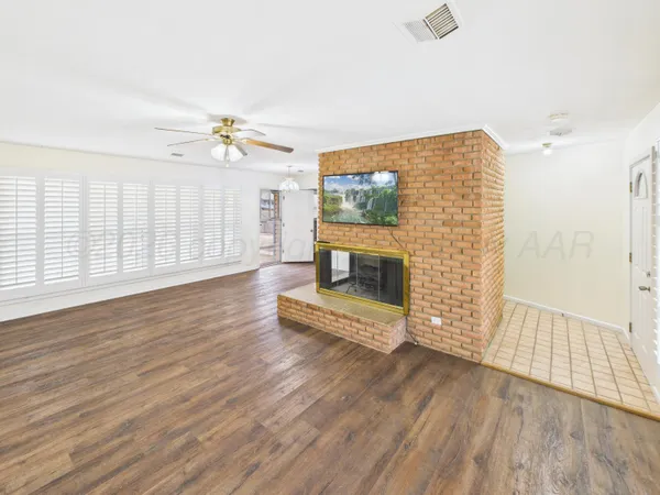 an empty room with wooden floor fireplace and windows