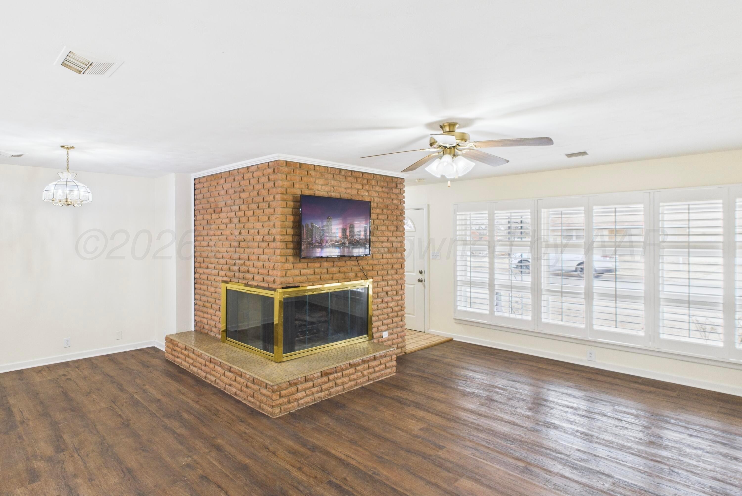 528 North Red Deer Street Pampa, TX 79065 - Photo 8 of 41 a living room with a fireplace furniture a ceiling fan and a wooden floor