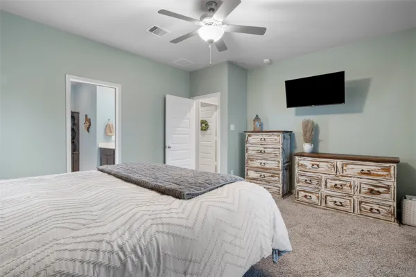a bedroom with a bed a dresser and a flat screen tv