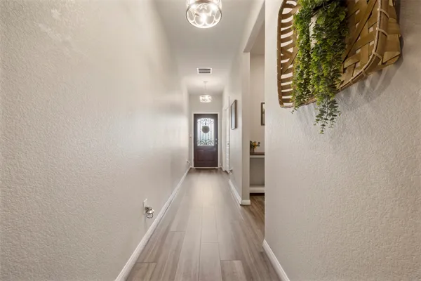 a view of a hallway with wooden floor and a bathroom