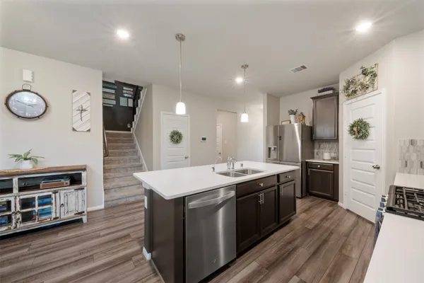 a kitchen with stainless steel appliances a stove refrigerator and wooden floor