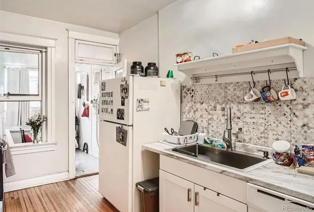 a white kitchen with sink and refrigerator