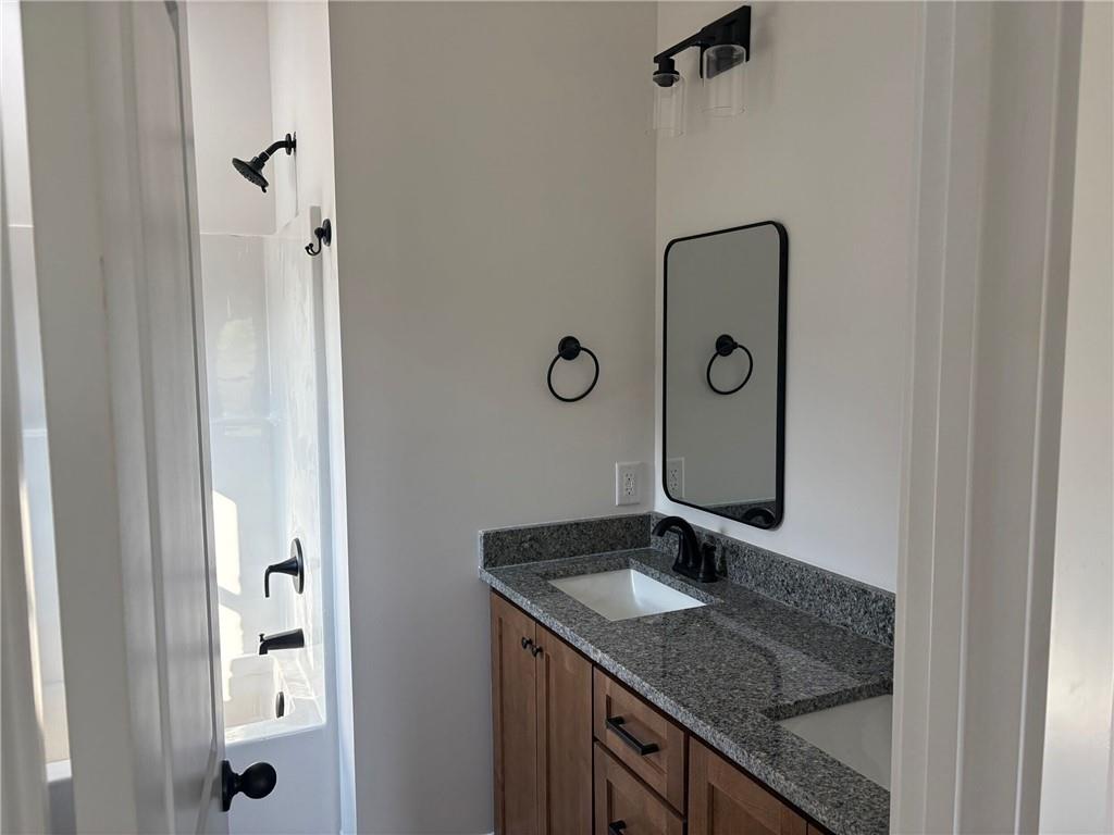 3216 South Phillips Road Lanett, AL 36863 - Photo 12 of 14 Bathroom featuring a dual-sink vanity with granite countertops, wood-finish cabinetry, and black hardware