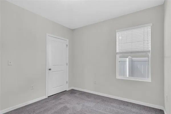 a view of an empty room with closet and a window