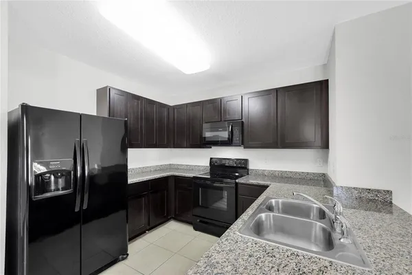 a kitchen with stainless steel appliances granite countertop a refrigerator a sink and a stove