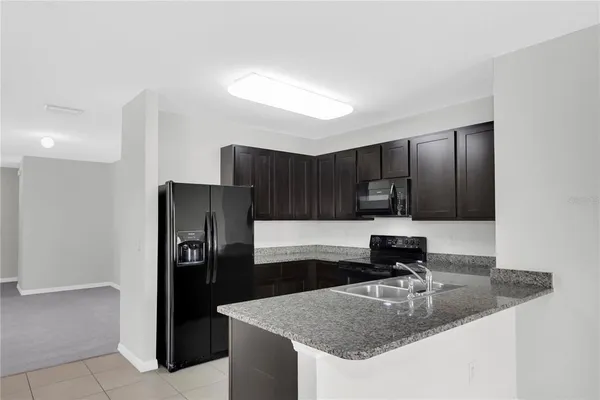 a kitchen with kitchen island granite countertop a refrigerator and a sink