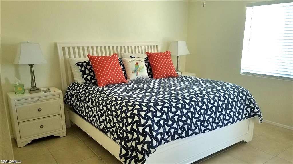 1075 Foxfire Lane, Unit 309 Naples, FL 34104 - Photo 7 of 33 a bedroom with a bed and a night stand next to a window