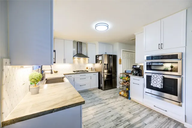 a kitchen with stainless steel appliances granite countertop a stove top oven a sink a dining table and chairs with wooden floor