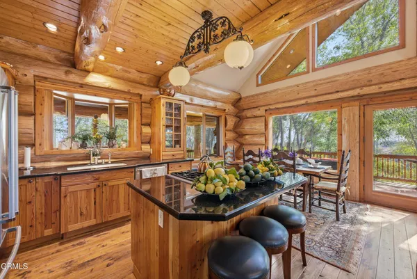 a view of a dining room with furniture one side kitchen view and wooden floor