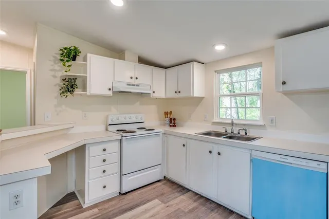 a kitchen with a refrigerator a sink cabinets and wooden floor