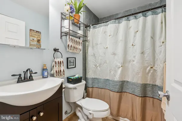 a bathroom with a sink a toilet a mirror a lamp and shower curtain