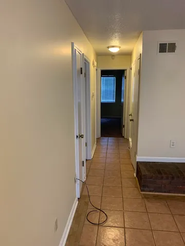 a view of a hallway with wooden floor and cabinet
