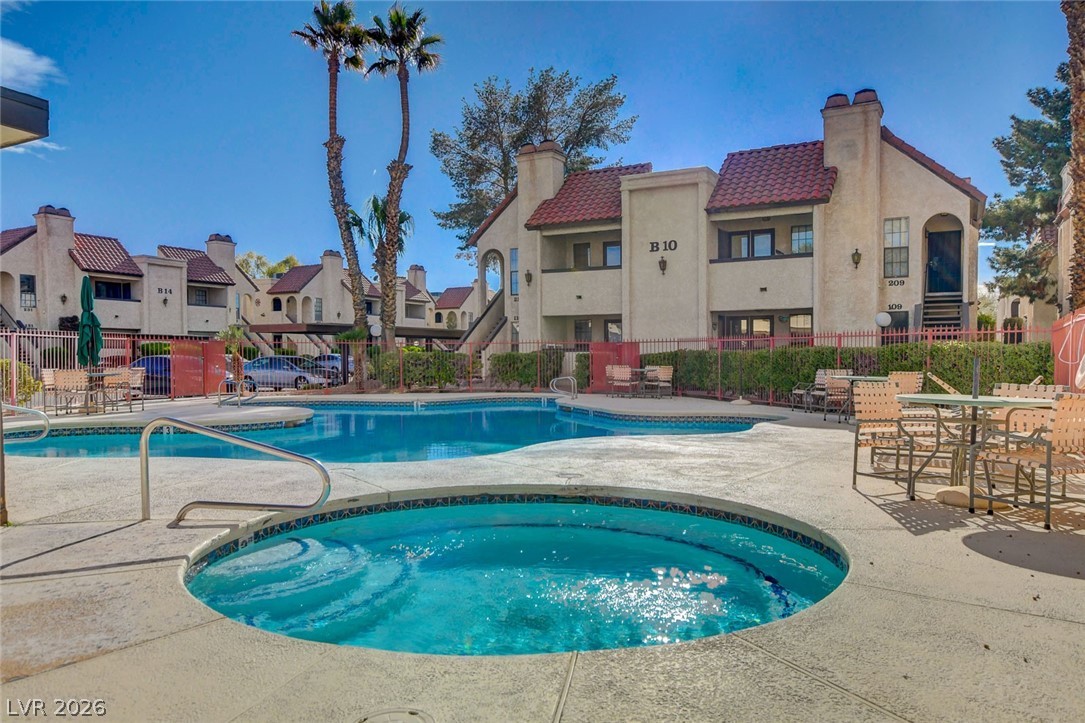 1751 East Reno Avenue, Unit 228 Las Vegas, NV 89119 - Photo 35 of 39 A pristine pool and hot tub beckon residents, set against a backdrop of classic stucco buildings with red tile roofs.