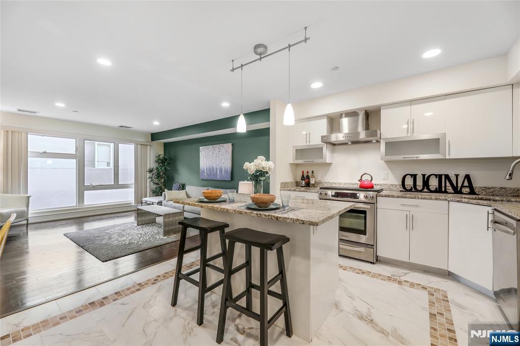 310 Cliff Lane, Unit 3C Cliffside Park, NJ 07010 - Photo 6 of 17 a kitchen with a stove a sink dishwasher a kitchen island with chairs and wooden cabinets