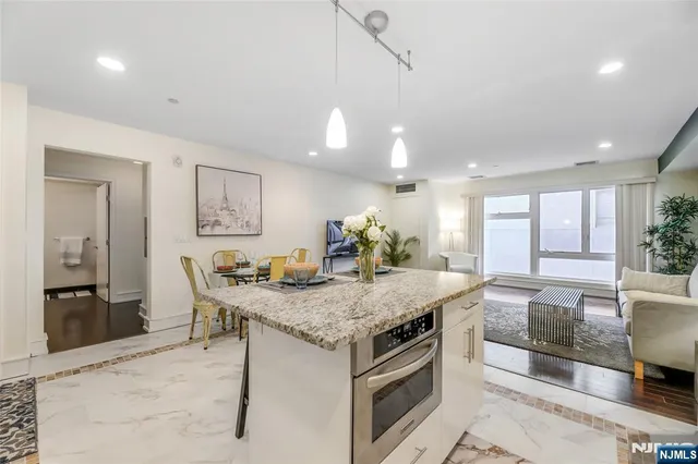 a kitchen with a stove a kitchen island and couches with wooden floor